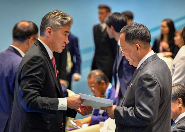 성 김(왼쪽) 필리핀주재 미국대사가 지난 4일 오후(현지시간) 싱가포르 엑스포 컨벤션센터에서 열린 아세안지역안보포럼(ARF) 포토세션이 끝난 뒤 리용호 북한 외무상에게 다가가 서류봉투를 전달하고 있다./싱가포르=로이터연합뉴스