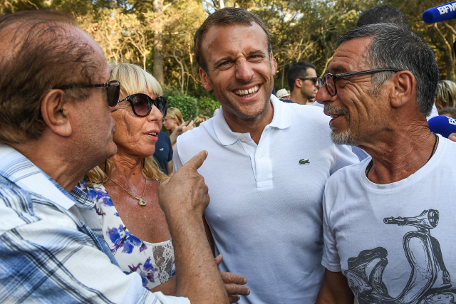 에마뉘엘 마크롱(가운데) 프랑스 대통령이 여름휴가 동안 머무르는 봄레미모사에서 이달 7일(현지시간) 주민들과 만나 밝게 웃고 있다. /봄레미모사=AFP연합뉴스