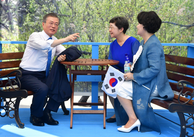 문재인 대통령이 15일 서울 용산구 국립중앙박물관 열린마당에서 열린 제73주년 광복절 및 정부수립 70주년 경축식을 마친 후 국가기록특별전을 찾아 남북정상회담 당시 도보다리를 재연한 포토존에 앉아 이소연 국가기록원장과 대화하고 있다. /연합뉴스