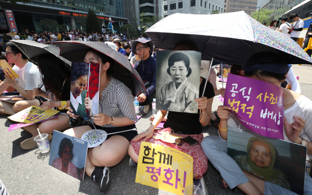 제73주년 광복절인 15일 서울 종로구 옛 일본대사관 앞에서 열린 ‘제6차 세계 일본군위안부 기림일 맞이 세계연대집회 1348차 정기수요시위’에서 참석자들이 위안부 피해 할머니들의 사진을 들고 있다. / 연합뉴스