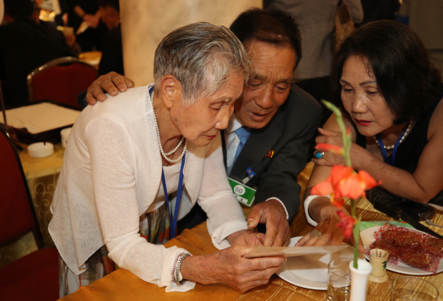 20일 오후 북한 금강산호텔에서 열린 이산가족 단체상봉에서 남측 이금섬(92) 할머니가 북측 아들 리상철(71) 씨와 만나 가족사진을 보고 있다./뉴스통신취재단=연합뉴스