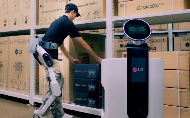 ‘LG 클로이 수트봇’을 착용한 작업자가 물류센터에서 상품을 쇼핑카트로봇에 옮겨담고 있다./사진제공=LG전자