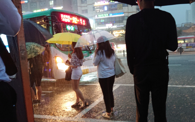 수도권지역에 폭우가 쏟아진 28일 오후 경기도 고양시 대화역 버스정류장에서 시민들이 우산을 쓴 채 버스를 타기 위해 이동하고 있다./연합뉴스