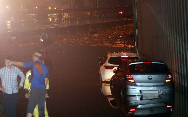 30일 새벽 홍수주의보가 내려진 중랑천 진입로에 차량들이 침수돼 있다./연합뉴스