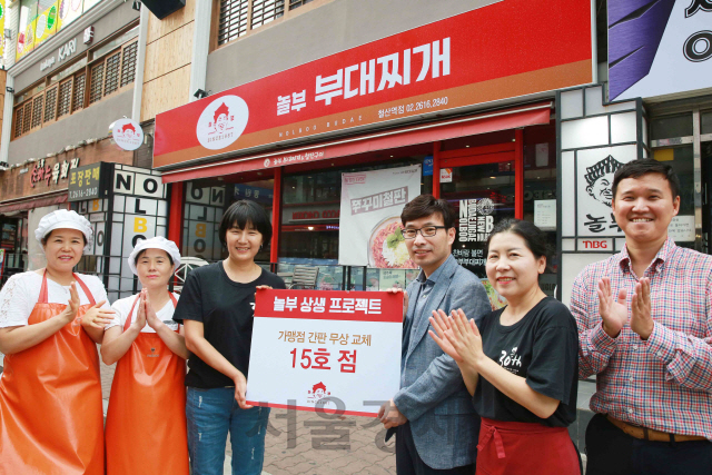 4일 종합외식전문기업 (주)놀부가 4일 놀부부대찌개 철산역점의 간판을 새로운 간판으로 무료 교체 지원한 가운데, 박은자 점주(왼쪽에서 세번째)를 비롯한 매장 직원들과 본사 상생협력팀 박용형 팀장(오른쪽에서 세번째)이 매장 앞에서 기념 촬영을 하고 있다. 해당 매장은 가맹점 간판 무상 교체 15호 점으로 놀부는 올 연말까지 70여개 매장을 대상으로 간판 교체 상생 프로젝트를 지속 실시할 계획이다/사진제공=(주)놀부