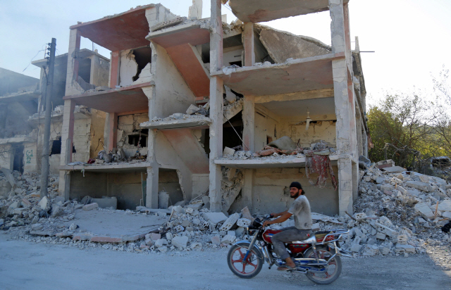 4일(현지시간) 시리아 북서부 반군 거점인 이들립주 지역에서 한 주민이 러시아군의 공습으로 파괴된 건물 앞을 지나가고 있다. /다마스쿠스=AFP연합뉴스