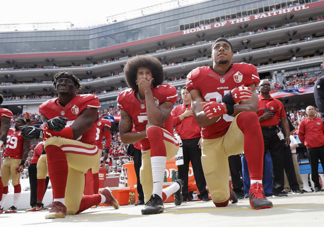 콜린 캐퍼닉(가운데)이 2016년 NFL경기 직전 국기에 대한 경례를 거부하고 무릎을 꿇고 있다. /AP=연합뉴스