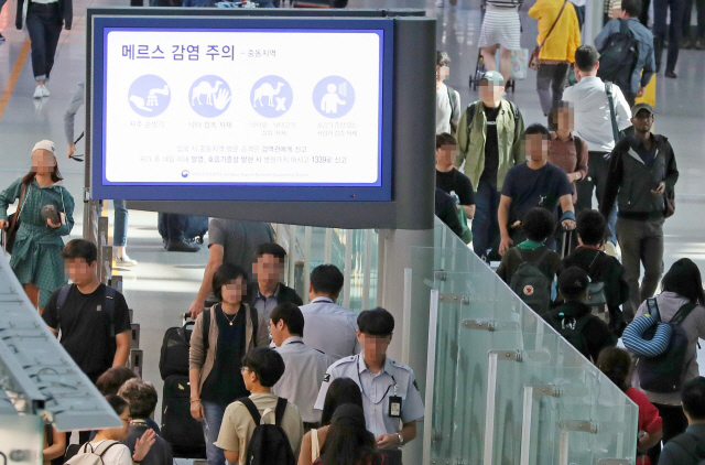 중동호흡기증후군(메르스) 방역에 비상이 걸린 9일 인천국제공항 이용객들이 메르스 주의 안내문 밑을 걸어가고 있다.  /인천=연합뉴스