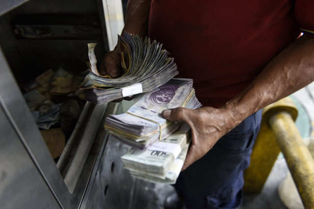 베네수엘라의 수도 카라카스에 있는 한 주유소에서 직원이 주유 후에 받은 돈을 세고 있다. 베네수엘라의 상당수 상인들은 현금 보관 비용이 훨씬 크다는 이유로 지폐를 받지 않고 신용카드로 결제를 하게 하고 있다. /블룸버그