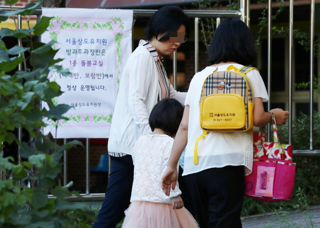 건물 붕괴 사고가 난 서울 상도유치원의 원아가 10일 오전 보호자와 함께 대체 수업 장소로 지정된 서울상도초등학교로 등원하고 있다./연합뉴스