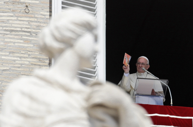 십자가상 너머의 프란치스코 교황이 지난 16일 바티칸 집무실에서 성 베드로 광장을 굽어보며 안젤로스 기도회를 인도하며 강론하고 있다./AP=연합뉴스
