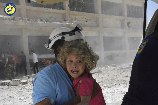 지난해 6월 14일(현지시간) 시리아 반군측 민간 구조대 하얀헬멧 대원이 시리아 남서부 다라에서 한 아이를 구출하고 있다./다라=AP연합뉴스
