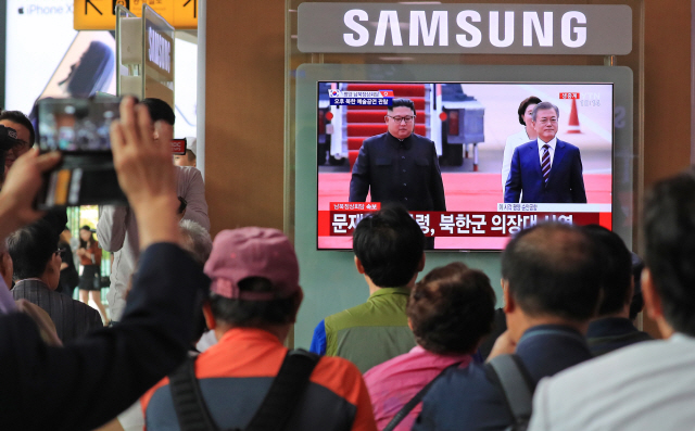 18일 오전 서울역 대합실에서 시민들이 문재인 대통령과 김정은 북한 국무위원장이 나란히 걷고 있는 모습을 시청하고 있다.  /권욱기자
