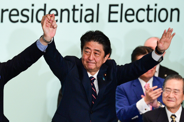 아베 신조 일본 총리가 20일 당선 후 집권 자민당 도쿄 당사에서 두 손을 들고 환호하고 있다.는 아베./AFP=연합뉴스