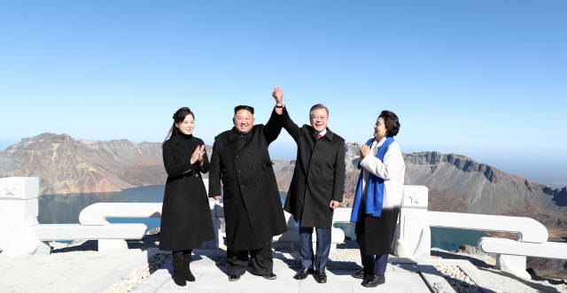 문재인 대통령과 김정숙 여사, 북한 김정은 국무위원장과 리설주 여사가 지난 20일 오전 백두산 정상인 장군봉에 올라 손을 맞잡고 들어 올리고 있다./평양사진공동취재단=연합뉴스