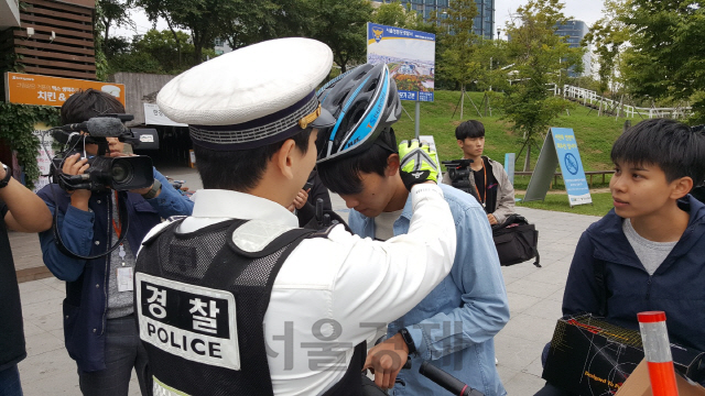 28일 오전 11시10분께 서울 영등포구 여의도 한강공원에서 안전모를 착용하지 않고 자전거를 타는 시민에게 경찰이 안전모를 씌워주고 있다./서종갑기자