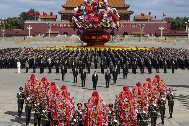 In this photo released by Xinhua News Agency, Chinese President Xi Jinping, center, is followed by high-ranking officials walk toward to the Monument to the People‘s Heroes during a ceremony marking Martyrs Day at Tiananmen Square in Beijing, Sunday, Sept. 30, 2018. Xi and other Chinese leaders presented flower baskets and scores of ordinary people filed up to lay a single flower each at the Peoples Heroes Monument in central Beijing to mark Martyrs Day. (Huang Jingwen/Xinhua via AP)      <저작권자(c) 연합뉴스, 무단 전재-재배포 금지>
