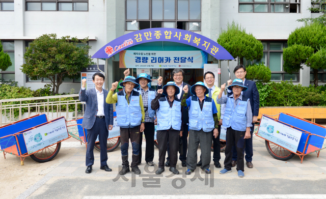 황대현(왼쪽 다섯번째) 기술보증기금 이사가 지난 4일 부산 감만종합사회복지관에서 폐지 수거 노인들에게 경량 리어카를 기부한 뒤 복지관 관계자들과 화이팅을 외치고 있다. /사진제공=기술보증기금