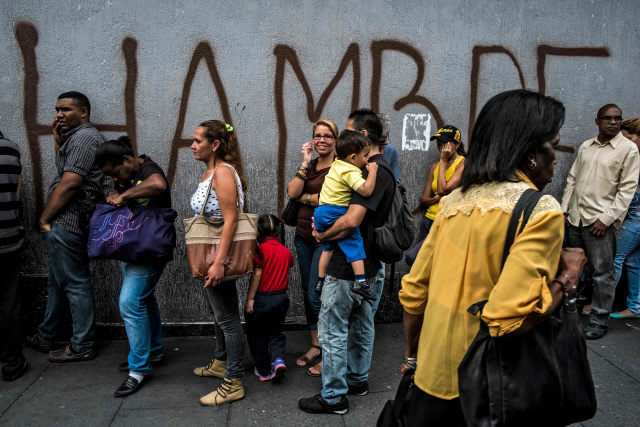 베네수엘라 수도인 카라카스에서 베네수엘라인들이 ‘배고픔’ 이라는 글이 쓰인 벽 앞에 줄을 서 있다./카라카스=AFP연합뉴스