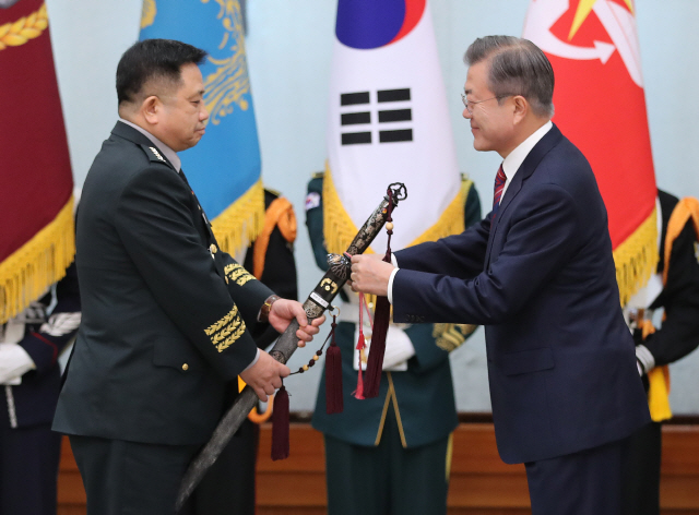 문재인 대통령이 12일 오전 청와대에서 열린 군 장성 진급 및 보직 신고식에서 박한기 신임 합참의장의 보직 신고를 받은 뒤 삼정검에 수치를 달아주고 있다./연합뉴스