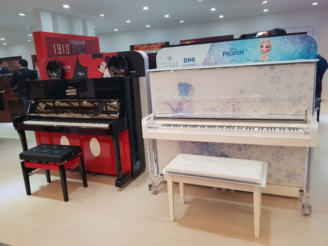 지난 12일(현지시간) 중국 상하이에서 열린 ‘뮤직차이나 2018’에 참가한 하이룬의 부스에 겨울왕국(오른쪽)과 미키마우스의 디자인을 차용한 피아노가 전시돼 있다./심우일기자