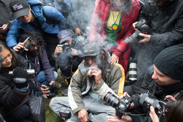 17일(현지시간) 캐나다 온타리오주 토론토에서 한 남성이 합법화된 마리화나를 피우고 있는 장면을 카메라 기자들이 촬영하고 있다. /토론토=AFP연합뉴스