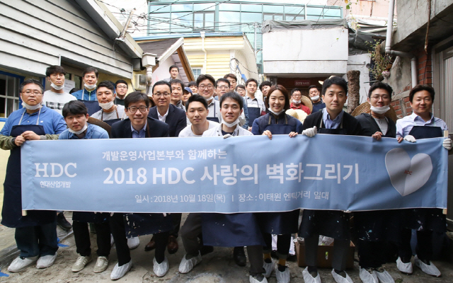 HDC현대산업개발 개발운영사업본부 임직원들이 18일 서울 용산구 이태원 앤틱가구거리 일원에서 ‘HDC 사랑의 벽화그리기’에 참여하고 기념 촬영을 하고 있다. 이번 활동은 연중 실시하는 ‘사랑나눔 릴레이’의 첫 행사로 HDC현대산업개발 임직원들은 연말까지 전 본부가 릴레이 형식으로 사회공헌활동을 이어간다. /사진제공=HDC현대산업개발