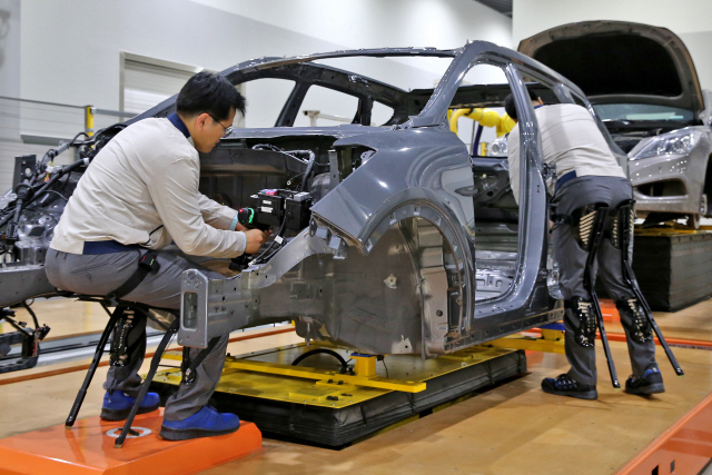 현대차 공장 작업자가 의자용착용로봇을 착용하고 차량을 조립하고 있다./사진제공=현대차