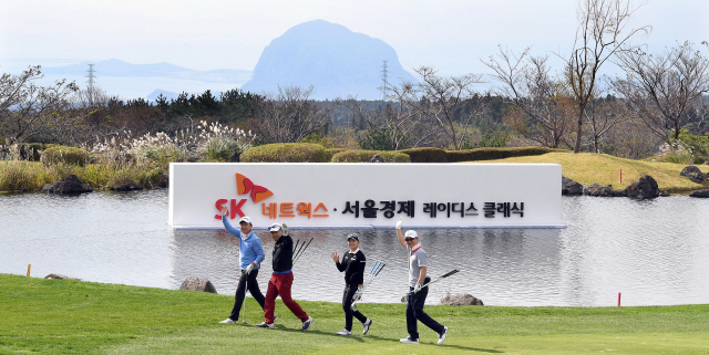 산방산이 저 멀리 보이는 18번홀 페어웨이를 지나는 이다연(왼쪽 세 번째)과 동반자들이 손을 흔들며 인사하고 있다.