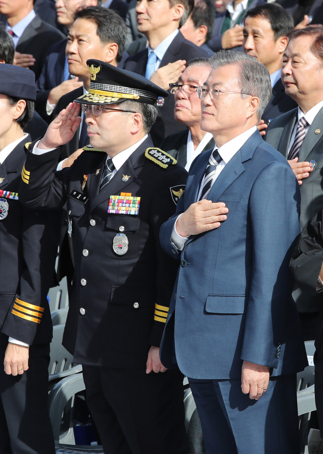 문재인 대통령이 25일 오후 서울 용산구 백범기념관에서 열린 제73주년 경찰의 날 기념식에 참석해 국기에 경례하고 있다. 왼쪽은 민갑룡 경찰청장. /연합뉴스