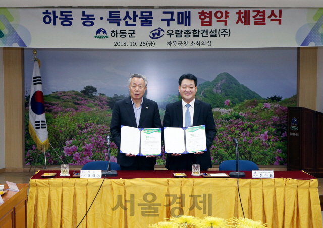 윤상기(왼쪽) 하동군수와 이수영 우람종합건설 대표가 협약서에 서명을 하고 들어 보이고 있다. /사진제공=하동군