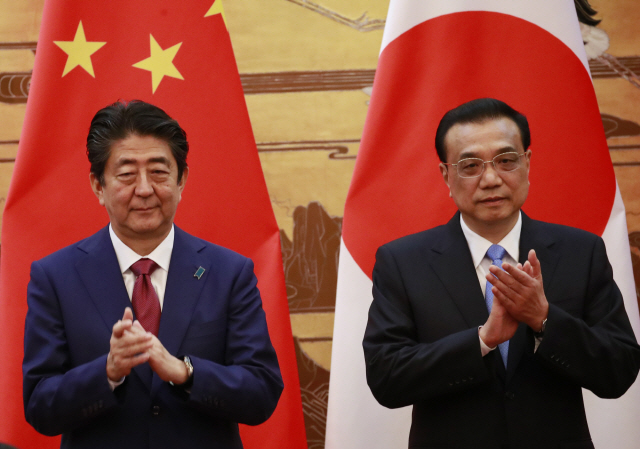 아베 신조(왼쪽) 일본 총리와 시진핑 중국 국가 주석과 만나기 전 리커창(오른쪽) 중국 총리와 함께 중국 베이징에서 열린 한 행사에서 박수를 치고 있다./사진=연합뉴스