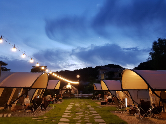 경기도 포천에 위치한 ‘푸른산페어웨이’에서 고기를 구워 먹으며 글램핑을 즐기고 있는 여행객들.