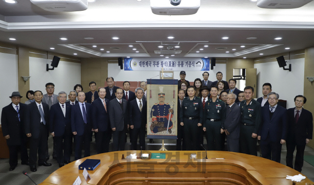 지난 2일 육군사관학교에서 열린 황석 부위 유품 기증식에서 황석의 종손자 황일주(영정 좌측) 씨와 정진경(중장, 영정 우측) 육사 교장 등 관계자들이 기념촬영하고 있다.