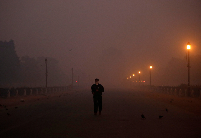 8일(현지시간) 인도의 수도 뉴델리에서 마스크를 쓴 한 남성이 미세먼지로 뒤덮인 전승 기념물 인디아 게이트를 지나가고 있다. /뉴델리=로이터연합뉴스