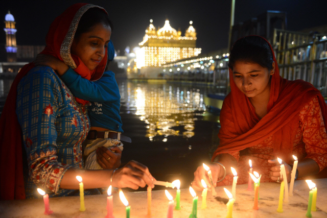 6일(현지시간) 인도 펀자브주 서부 암리차르의 골든 사원에서 여성들이 디왈리 축제를 기리는 촛불을 붙이고 있다. /암리차르=AFP연합뉴스