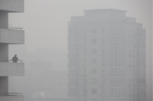 한 남성이 미세먼지로 가득한 중국 베이징의 한 건물 발코니에 서 있다. /베이징=블룸버그