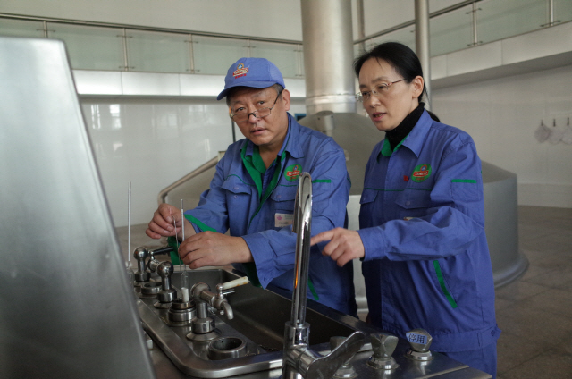 장 페이(오른쪽) 칭따오 양조장 총 브루마스터가 직원과 함께 맥주 생산 과정에서 맥아 농도를 살펴보고 있다. /김경미기자