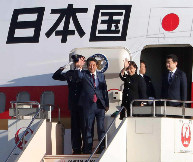 아베 신조(왼쪽 두 번째) 일본 총리가 부인 아키에(가운데) 여사와 함께 14일(현지시간) 도쿄의 하네다공항에서 동남아시아국가연합(ASEAN) 관련 정상회의가 열리는 싱가포르로 출발하기에 앞서 전용기에 올라 손을 흔들며 인사하고 있다. /도쿄=AFP연합뉴스