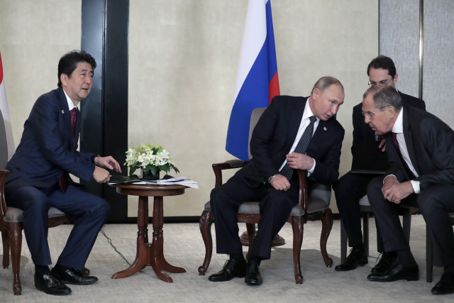 아베 신조(왼쪽) 일본 총리가 14일(현지시간) 싱가포르에서 블라디미르 푸틴(가운데) 러시아 대통령과 정상회담을 하고 있다. /싱가포르=EPA연합뉴스