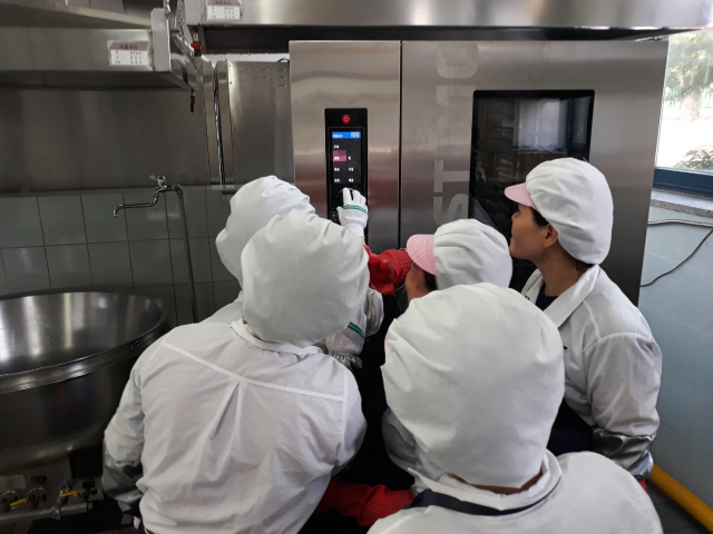 한 중학교의 급식 조리사들이 효신테크가 국내 최초로 선보인 내장형 훈연 기능 탑재 상업용 오븐을 관심있게 바라보고 있다. /사진제공=효신테크