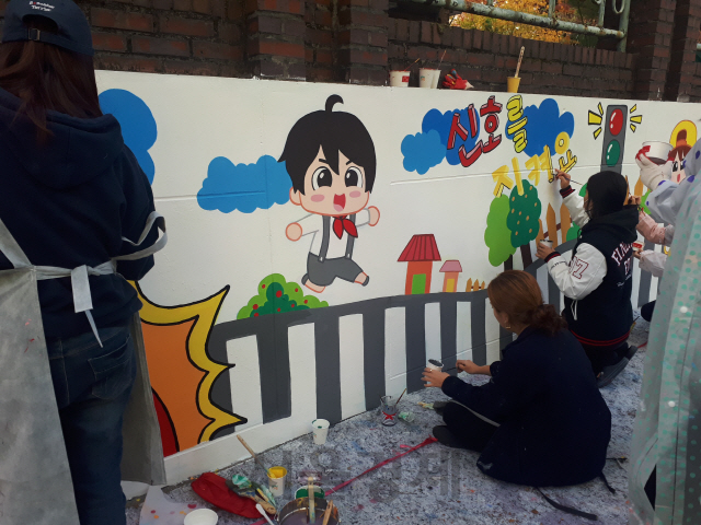 지난 22일 재능기부 자원봉사자들이 서울 구산초등학교 담장에 어린이 교통안전을 주제로 벽화를 그리고 있다. /사진제공=한국교통안전공단
