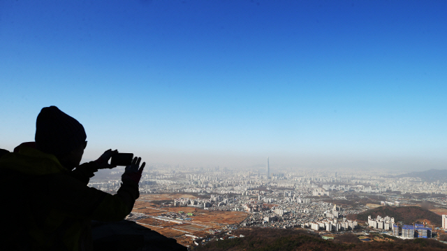 미세먼지 농도가 ‘나쁨’ 수준을 보인 28일 오전 경기도 광주시 남한산성에서 시민들이 파란 하늘 아래 미세먼지 덮인 서울 시내를 휴대전화기로 촬영 하고 있다./연합뉴스