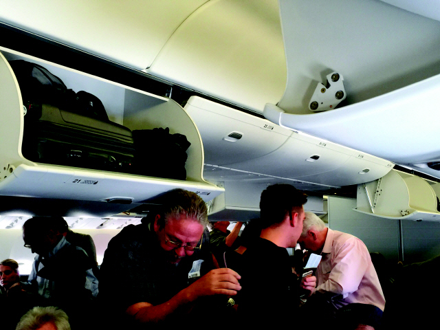 비행기 짐칸의 높이 때문에 머리를 부딪히는 승객의 모습.