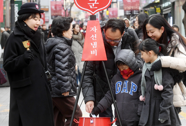 구세군 자선냄비 모금활동이 시작된 30일 오후 서울 중구 명동거리에서 한 가족이 자선냄비에 성금을 넣고 있다./권욱기자