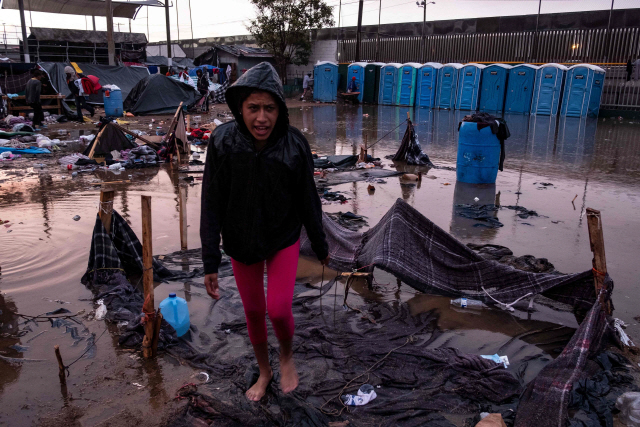 29일(현지시간) 미국 샌디에이고와 국경이 접한 티후아나시에 마련된 이민자 보호시설에서 한 여성 이민자가 폭우에 무너진 자신의 임시텐트를 바라보며 안타까워 하고 있다. /티후아나=AFP연합뉴스