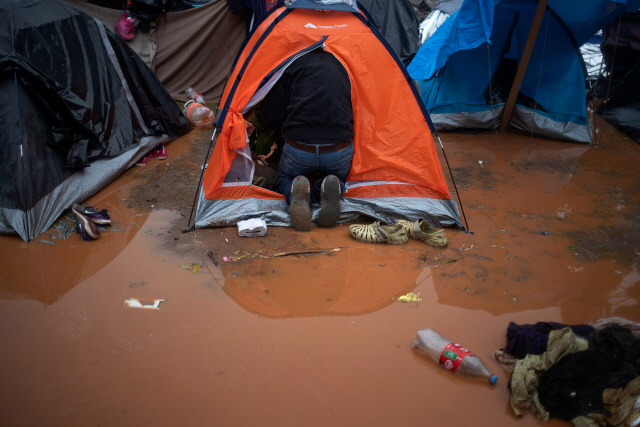 29일(현지시간) 미국 샌디에이고와 국경이 접한 티후아나시에 마련된 이민자 보호시설에서 한 이민자가 물이 들어찬 자신의 텐트를 들여다 보고 있다. /티후아나=로이터연합뉴스
