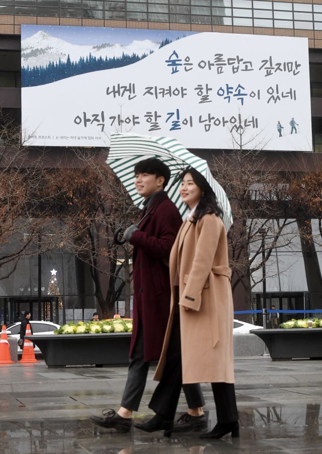 3일 새 옷으로 갈아입은 서울 교보생명 광화문글판 앞에서 한 대학생 커플이 길을 걷고 있다. 이번 교보생명 광화문글판 '겨울편'은 로버트 프로스트의 시 '눈 내리는 저녁 숲가에 멈춰 서서'에서 가져왔다./권욱기자