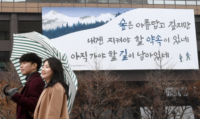 3일 새 옷으로 갈아입은 서울 교보생명 광화문글판 앞에서 한 대학생 커플이 길을 걷고 있다. 이번 교보생명 광화문글판 ‘겨울편’은 로버트 포레스트의 시 ‘눈 내리는 저녁 숲가에 멈춰 서서’에서 가져왔다./권욱기자