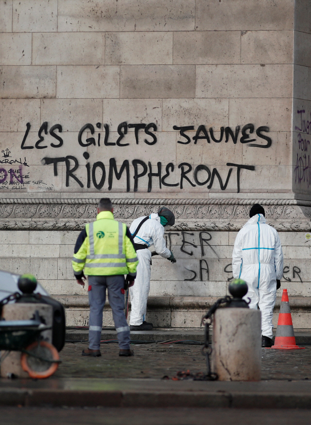 2일(현지시간) 프랑스 수도 파리에서 전문가들이 “노란 시위가 승리할 것”이라고 적힌 개선문 벽면을 청소하고 있다.  /파리=로이터연합뉴스